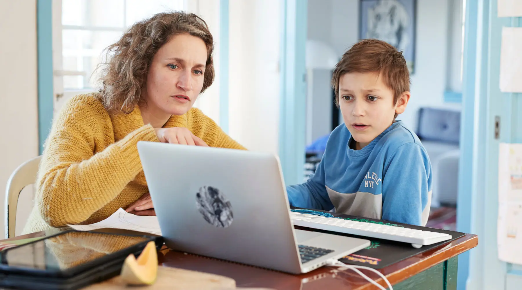 Mother homeschooling son at laptop